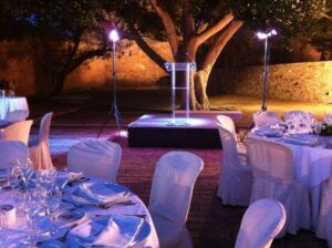 Clear methacrylate lectern on a stage surrounded by tables set for an outdoor event