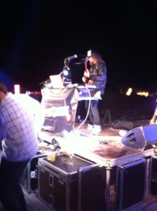 A live DJ and guitarist performing on stage with professional audio and lighting equipment during an outdoor event in Malaga