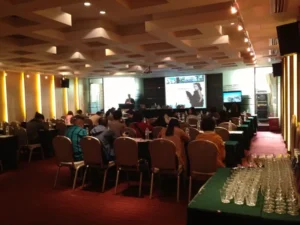 Setup for a MICE event in Malaga with a podium, professional lighting, sound equipment, a large screen displaying a presentation, and a projector in a modern conference venue.