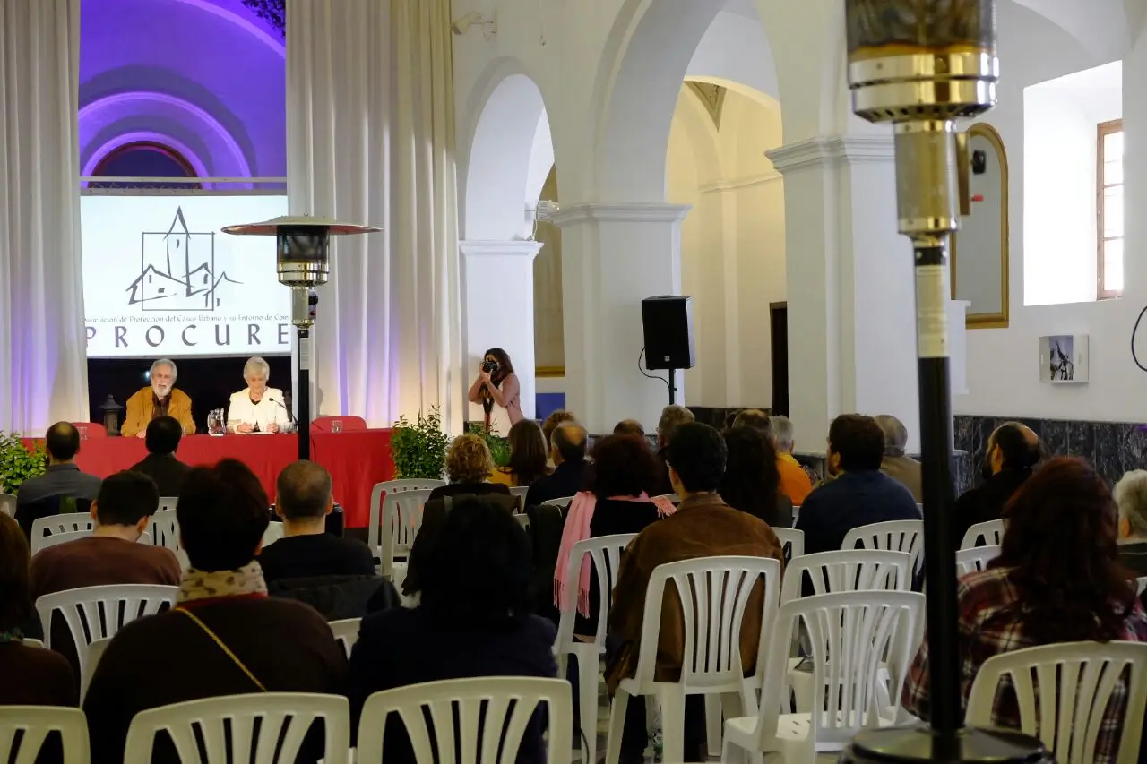 Setup for a MICE event in Malaga with a podium, professional lighting, sound equipment, a large screen displaying a presentation, and a projector in a modern conference venue.