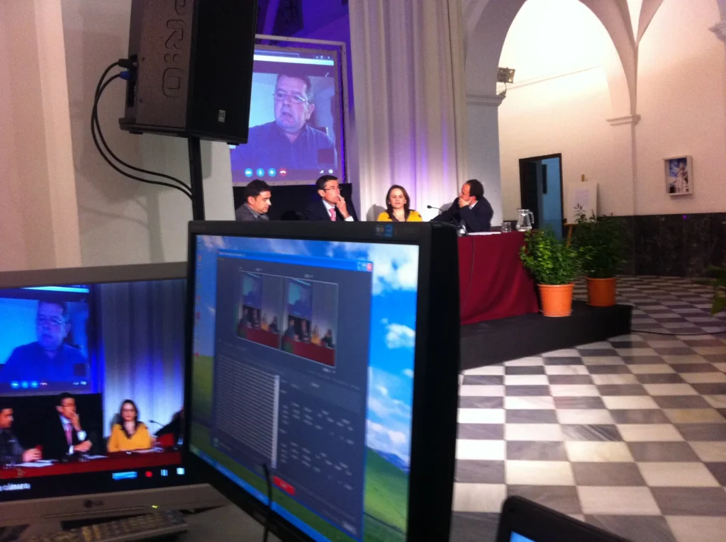 Setup for a MICE event in Malaga with a podium, professional lighting, sound equipment, a large screen displaying a presentation, and a projector in a modern conference venue.