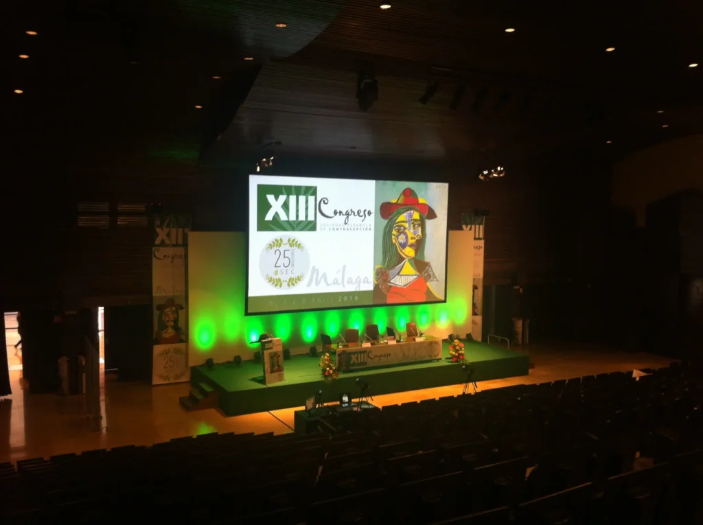 Audiovisual rental setup for a congress in Malaga, including a big screen, projector, LED lighting, podium, and sound system, Malaga.