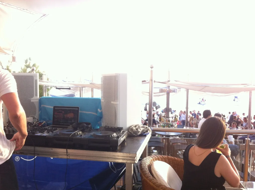 Audio system rental setup in Malaga for a beachside party, featuring professional DJ equipment, speakers, and a lively crowd enjoying the event.