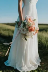 A bride in a white wedding gown holding a beautiful pastel floral bouquet.