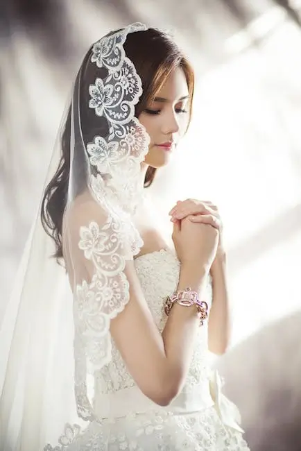 Bride in lace veil praying before her wedding ceremony.
