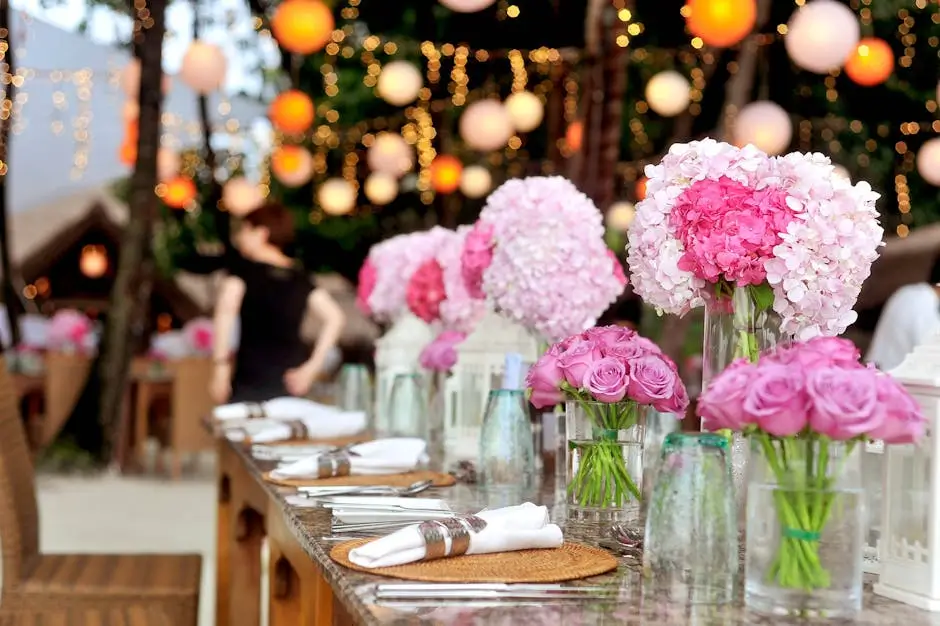 Wedding reception table with pink flowers and lights.