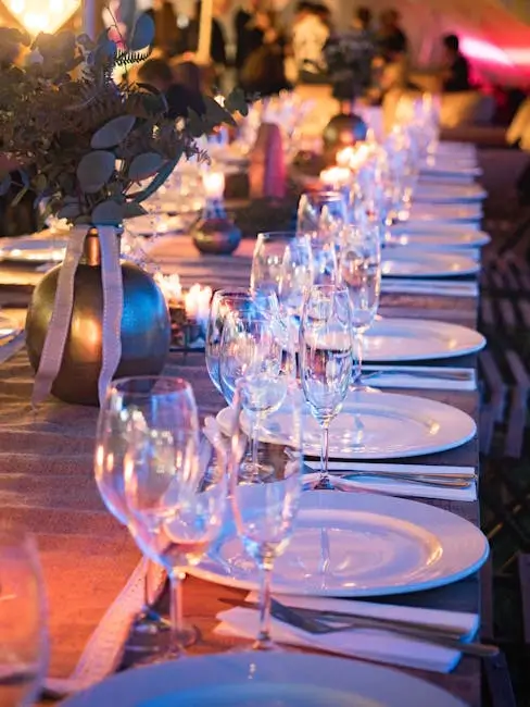 Long wedding dinner table set with glassware, plates, and floral decor.