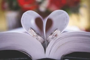 Two wedding rings are placed inside a book, forming a heart shape, wedding rings.