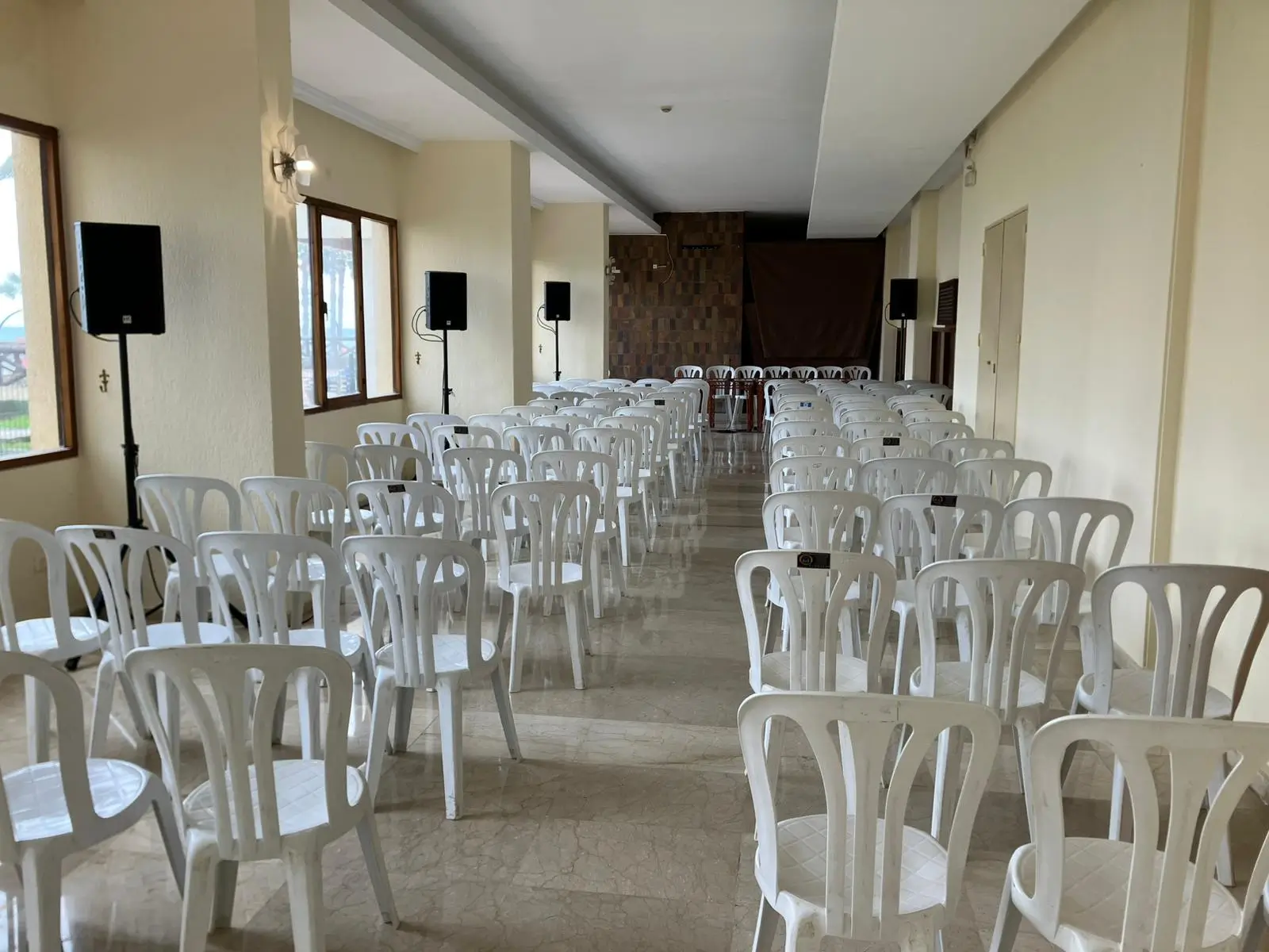 Empty community meeting room set up with white chairs and sound system rental equipment in Malaga, Spain.